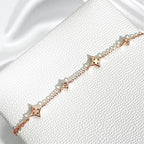 Stone Twilight Hand Chain Bracelet in rose 14k gold with star-shaped charms on a white textured surface