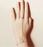 Hand wearing a Hand Chain Bracelet in Sterling Silver and white gold hand chain on a plain background