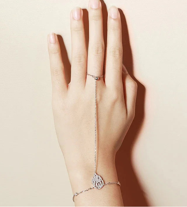Hand wearing a Hand Chain Bracelet in Sterling Silver and white gold hand chain on a plain background