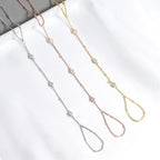 Three hand chain bracelets in gold, silver, and rose gold on a white surface