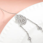 A diamond encrusted ornate centerpiece in the middle of a Hand Chain Bracelet in Sterling Silver and white gold diamond motif clasp on a white surface