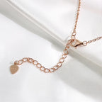 Rose 14k gold Stone Twilight Hand Chain Bracelet clasp with a heart-shaped tag on a white fabric background